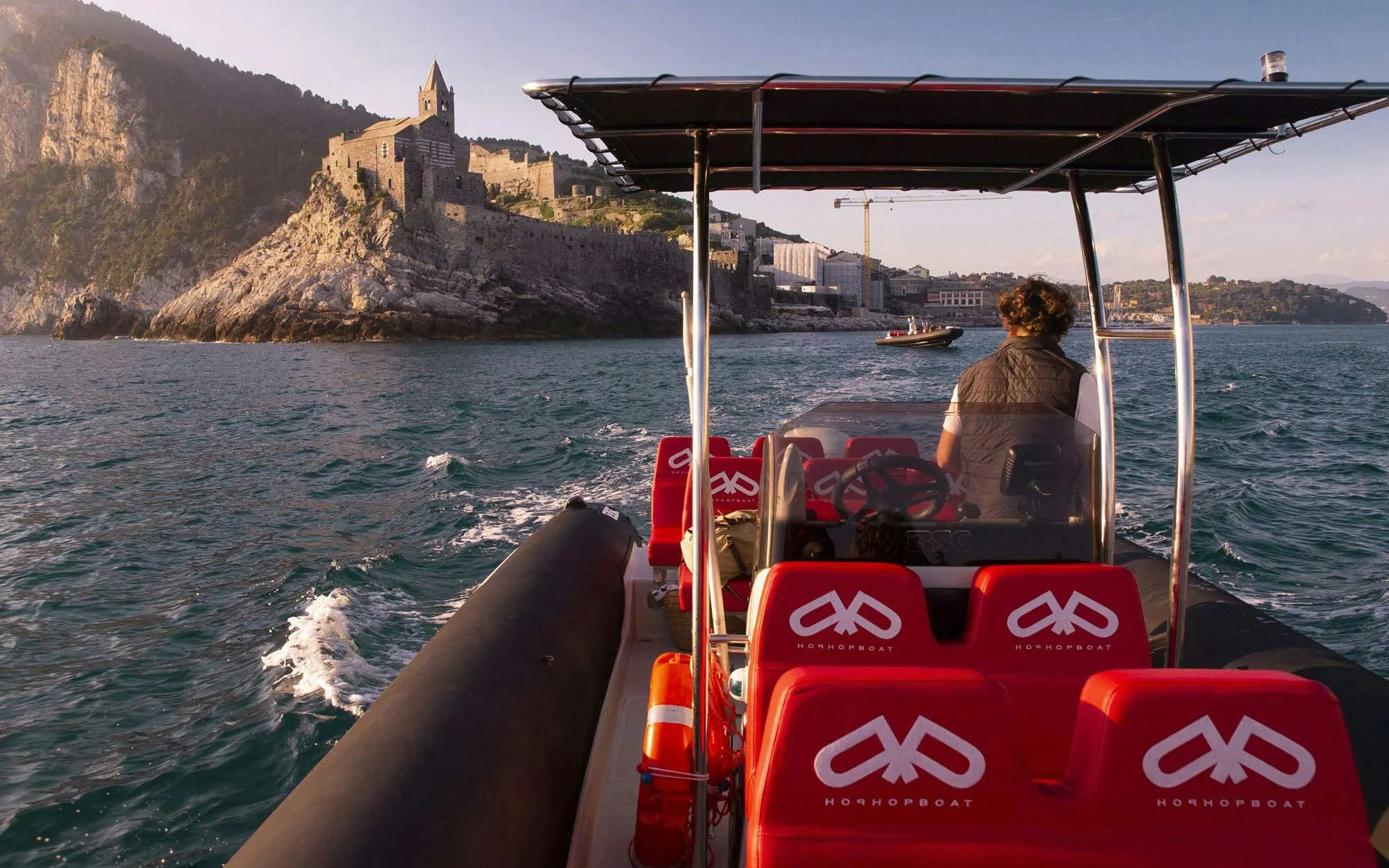 Boat approaching Portovenere with view of historic church on cliff, La Spezia boat trip.