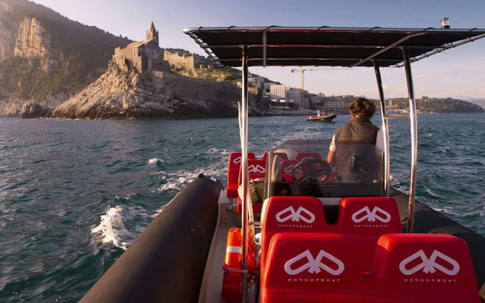 Boat approaching Portovenere with view of historic church on cliff, La Spezia boat trip.