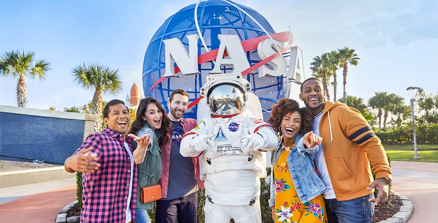 Visitors posing with astronaut in front of NASA globe at Kennedy Space Center, Florida.