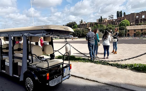 Golf cart parked near tourists at Circus Maximus, Rome, during express tour.