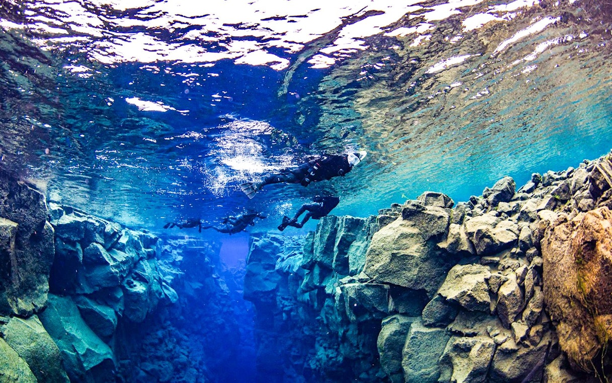 Snorkelers exploring underwater rift during Snorkeling between two continents tour.