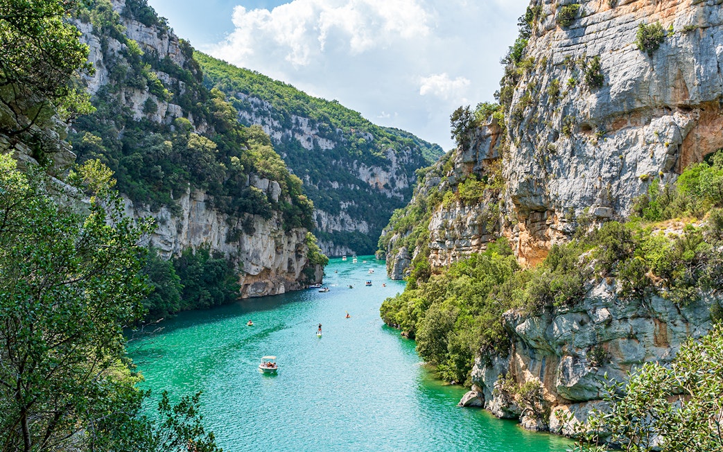 Turquoise waters and cliffs of Verdon Gorges, France, with boats and kayaks.