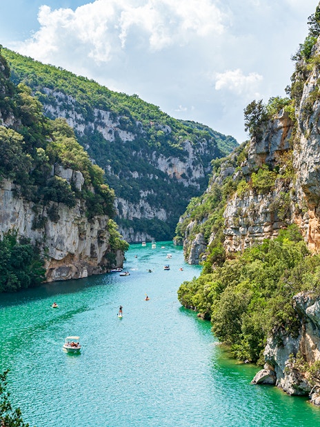 Turquoise waters and cliffs of Verdon Gorges, France, with boats and kayaks.