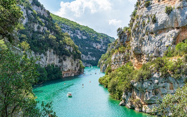 Turquoise waters and cliffs of Verdon Gorges, France, with boats and kayaks.