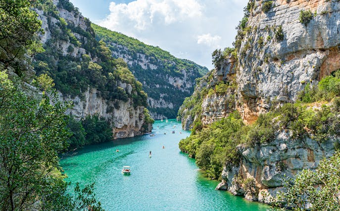 Turquoise waters and cliffs of Verdon Gorges, France, with boats and kayaks.