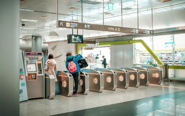 Travelers using KORAIL Pass at Seoul train station turnstiles.