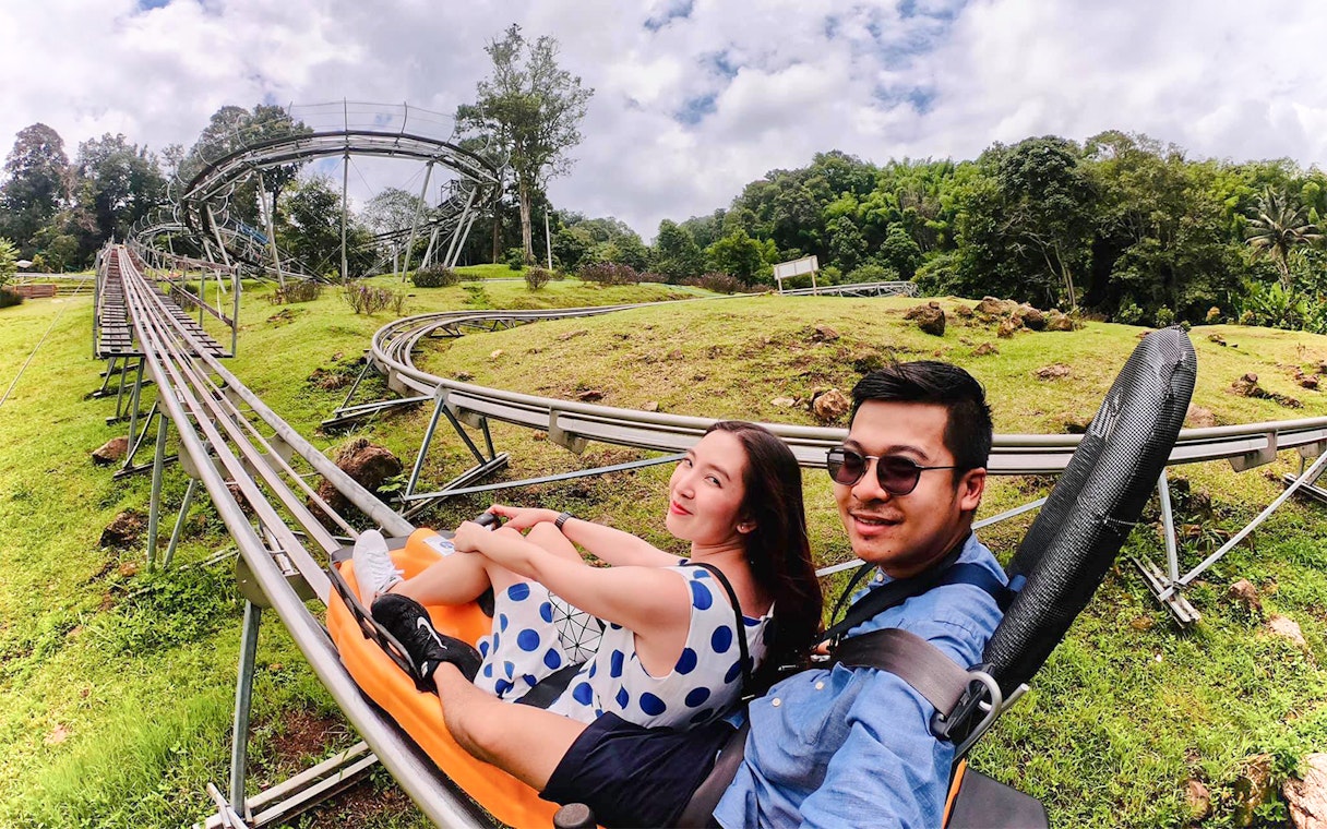 Couple enjoying a scenic coaster ride through lush greenery.