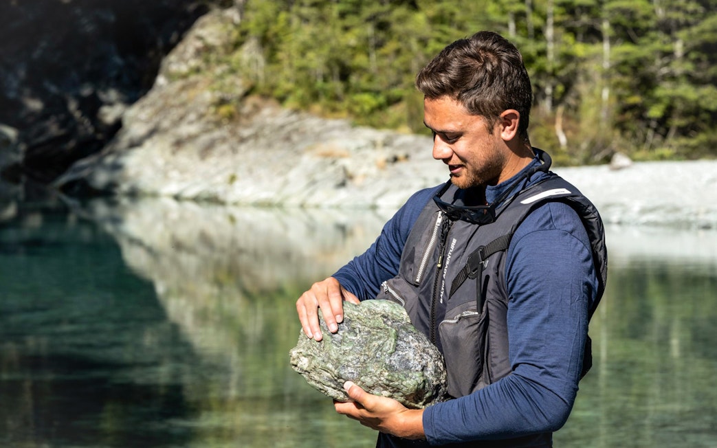Man holding a rock by the Dart River during Wilderness Jet Experience in New Zealand.