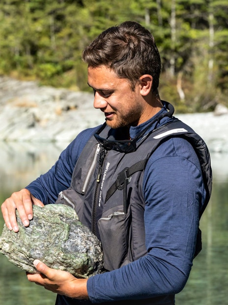 Man holding a rock by the Dart River during Wilderness Jet Experience in New Zealand.