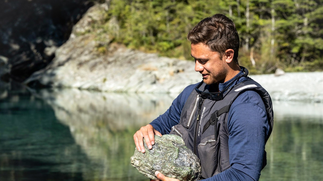 Man holding a rock by the Dart River during Wilderness Jet Experience in New Zealand.