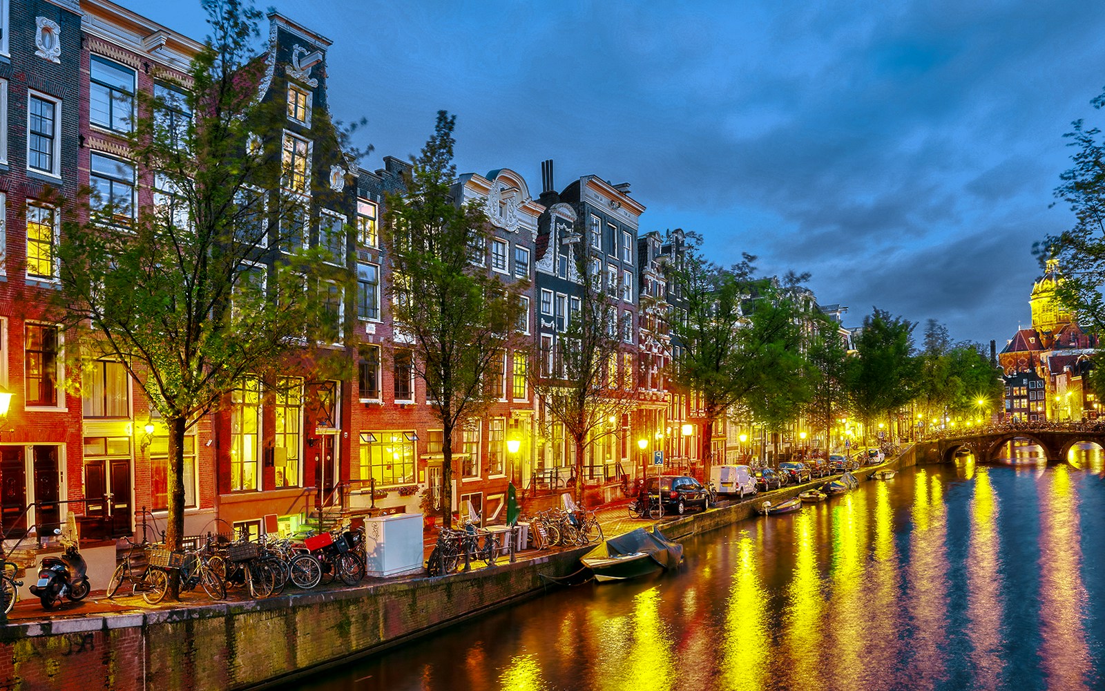 Prinsengracht canal in Amsterdam at night with illuminated buildings and reflections.