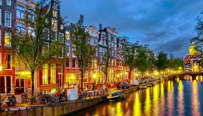 Prinsengracht canal in Amsterdam at night with illuminated buildings and reflections.