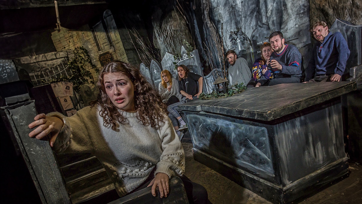 Tourists experiencing the eerie Kirkyard scene at The Edinburgh Dungeon in Scotland.