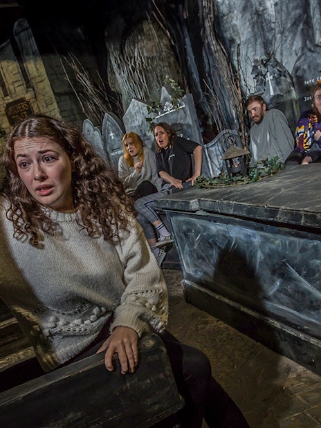 Tourists experiencing the eerie Kirkyard scene at The Edinburgh Dungeon in Scotland.