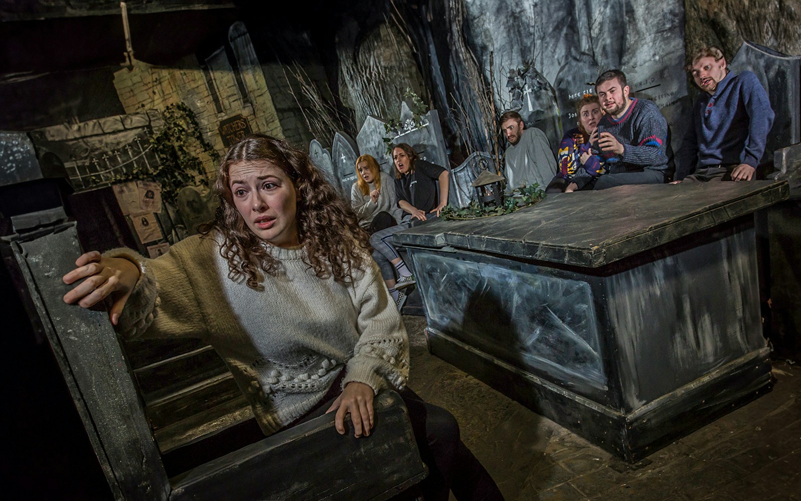 Tourists experiencing the eerie Kirkyard scene at The Edinburgh Dungeon in Scotland.