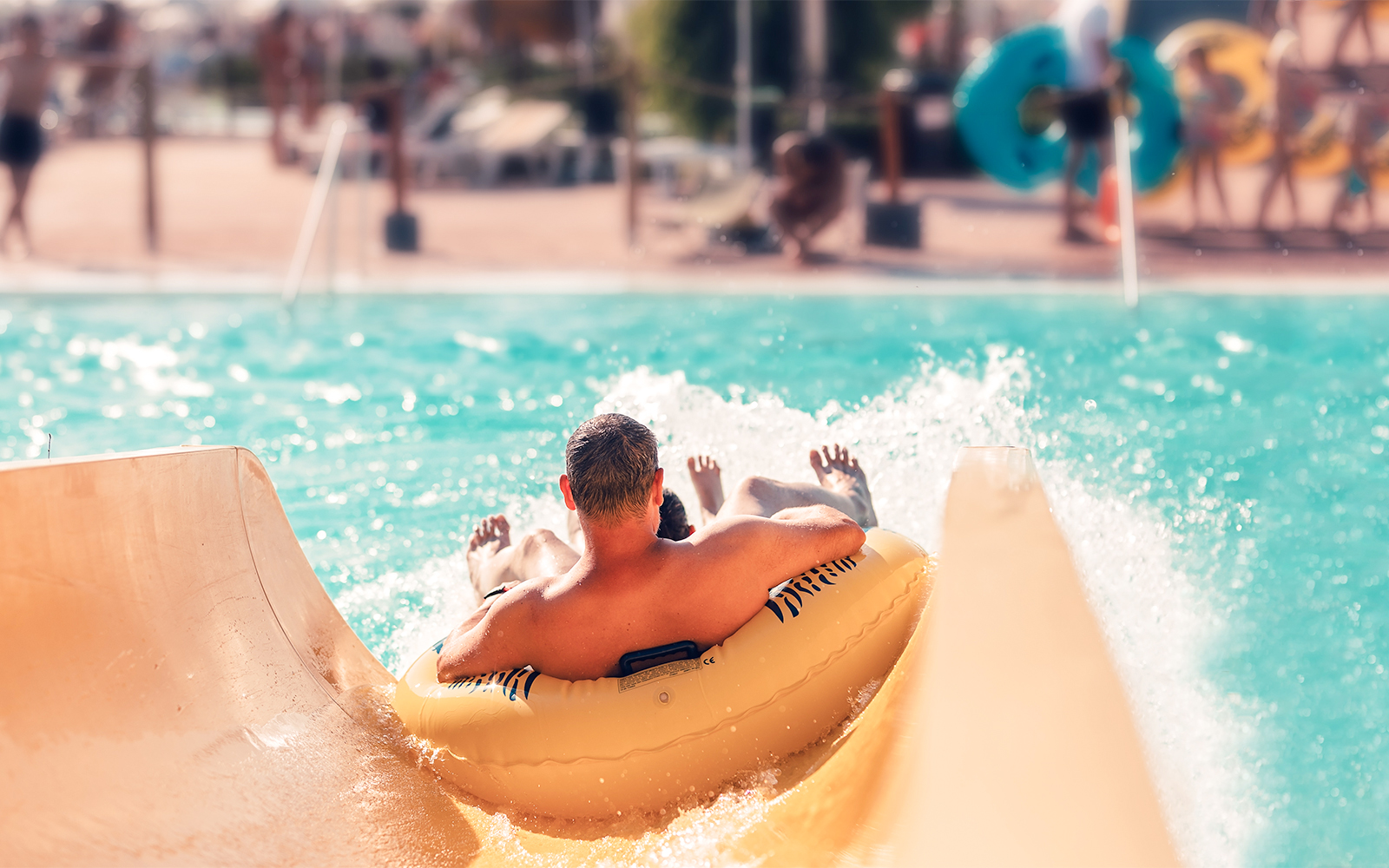 Man on inflatable tube sliding into pool at AquaVera Water Park.