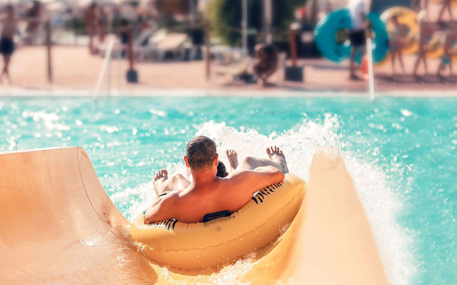 Man on inflatable tube sliding into pool at AquaVera Water Park.