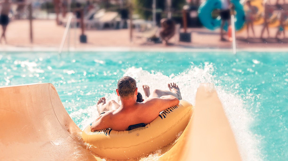 Man on inflatable tube sliding into pool at AquaVera Water Park.