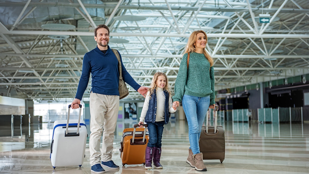Family with luggage walking through Gatwick Airport terminal.