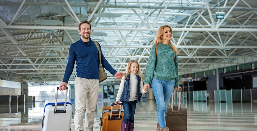 Family with luggage walking through Gatwick Airport terminal.