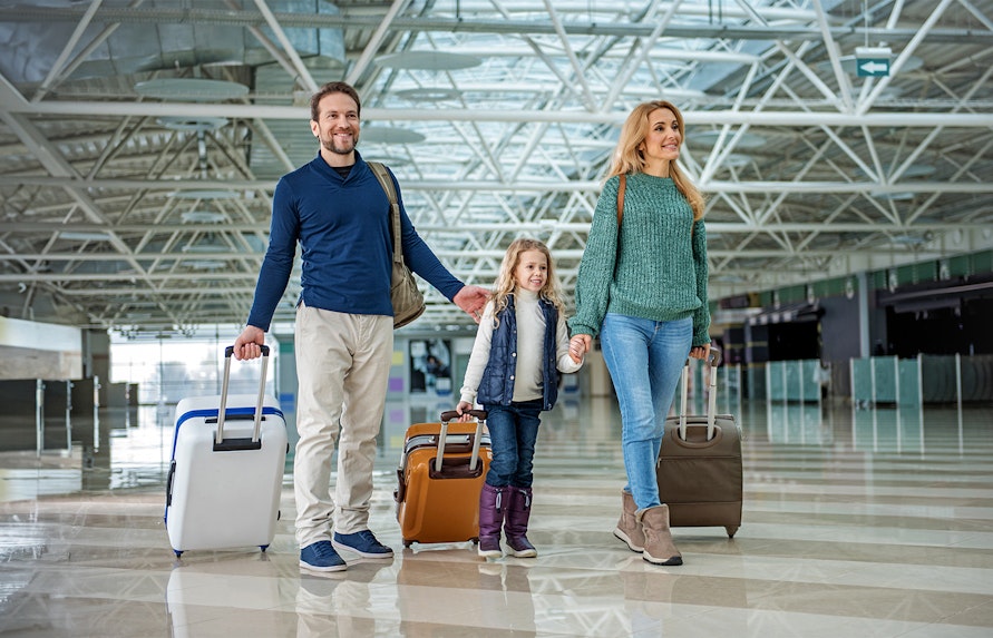Family with luggage walking through Gatwick Airport terminal.
