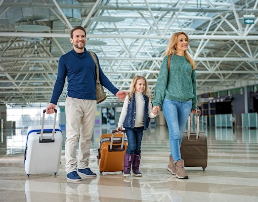 Family with luggage walking through Gatwick Airport terminal.