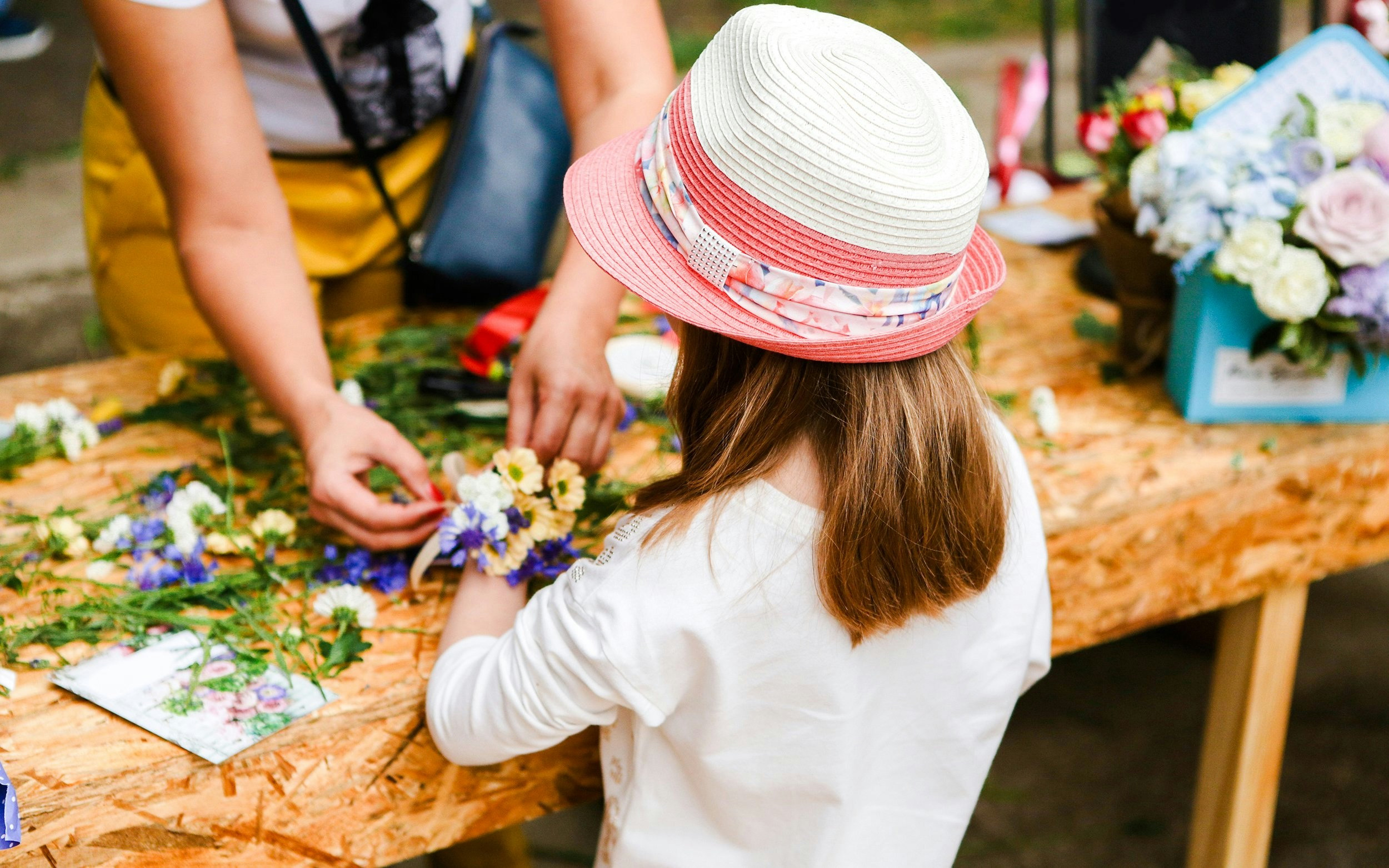Child participating in a flower arranging activity at a gardening workshop in Versailles.