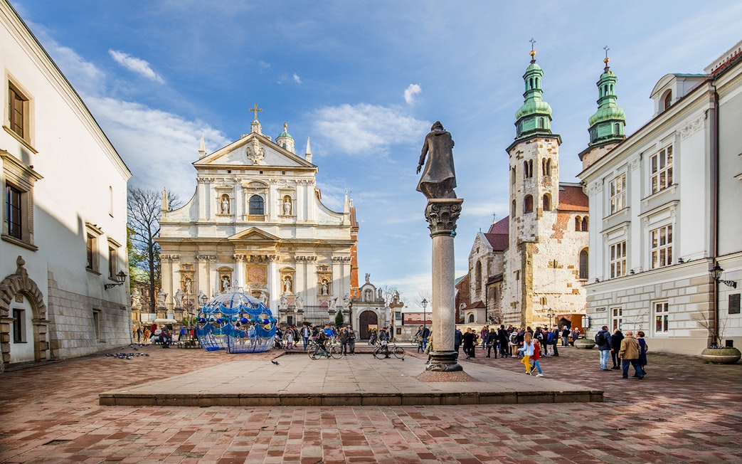 Krakow Old Town square with Saint Mary's Basilica and tourists exploring.