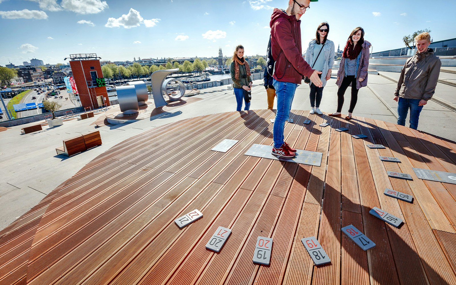 Visitors exploring rooftop terrace at NEMO Science Museum, Amsterdam, with city skyline views.