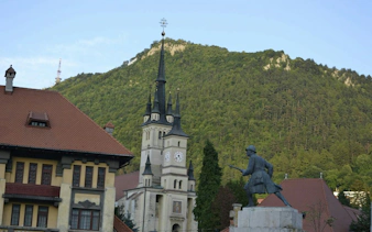 Church and statue in Schei district with Tampa Mountain, Brașov in the background.