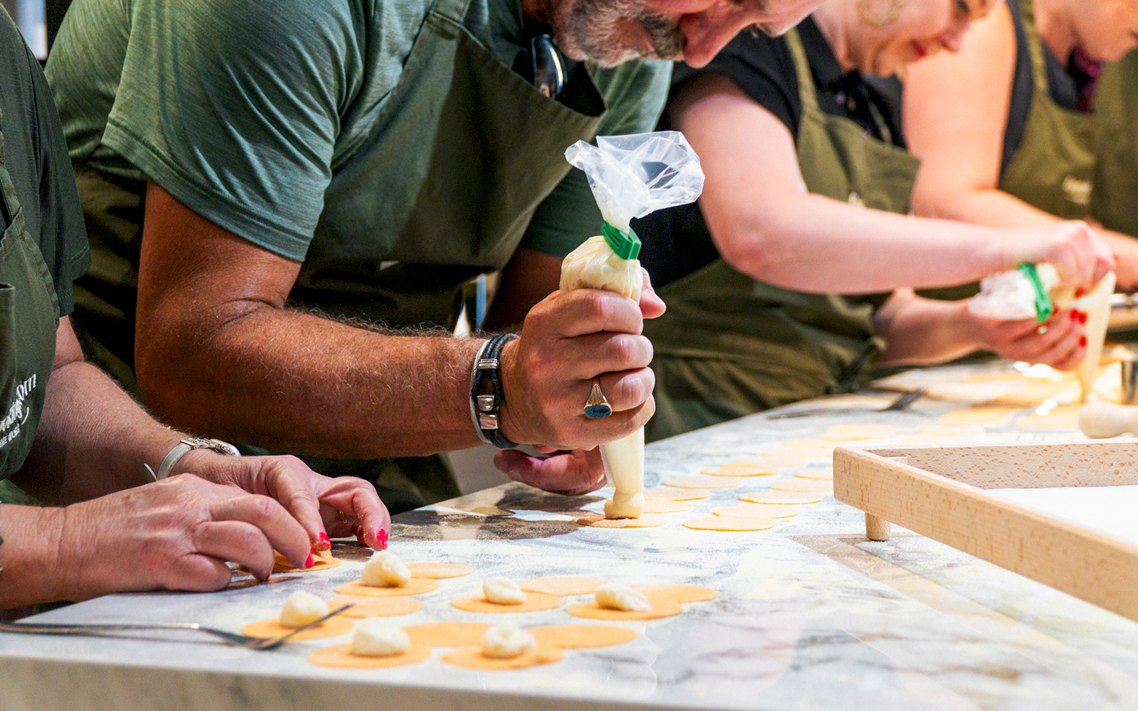 Participants shaping pasta dough in a hands-on pasta making class.