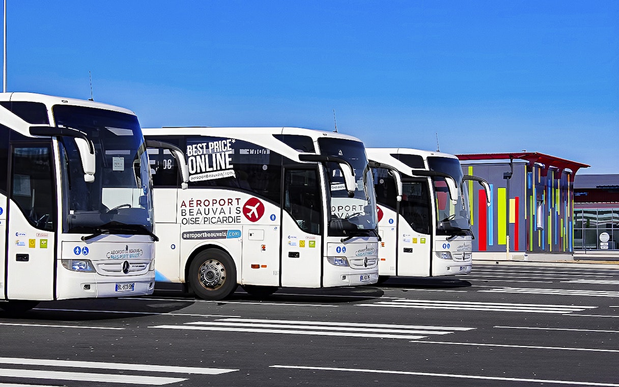 Aerobus Paris parked at airport with colorful terminal building in background.