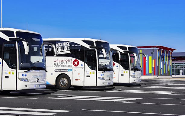 Aerobus Paris parked at airport with colorful terminal building in background.