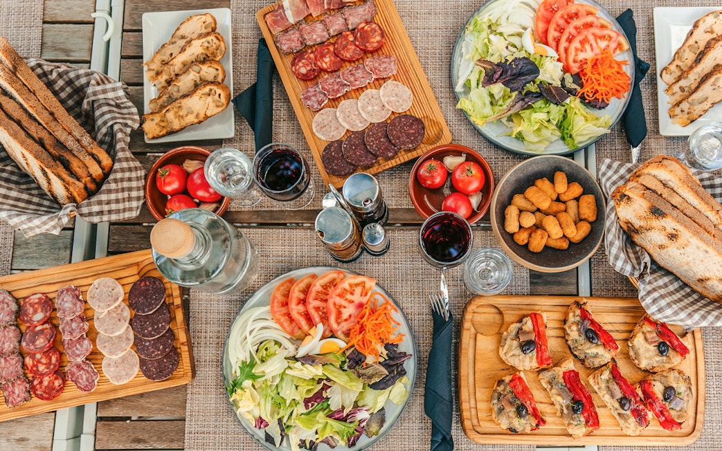 Lunch spread with charcuterie, salad, bread, and wine on Montserrat monastery tour.