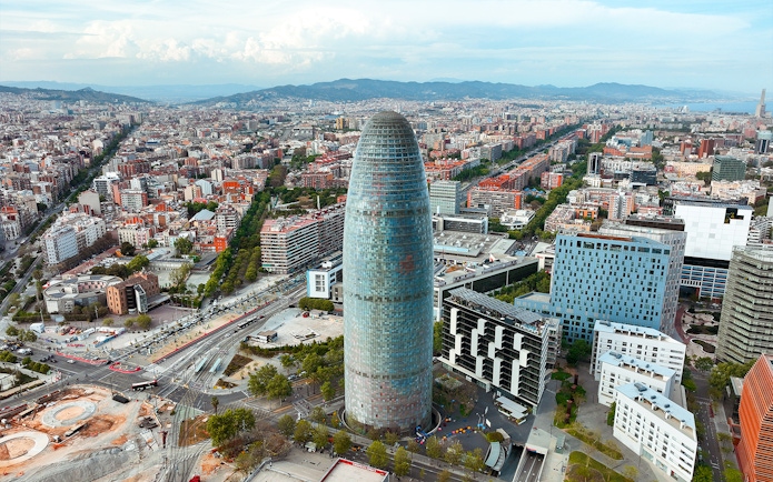 Aerial view of Torre Glòries in Barcelona surrounded by cityscape.
