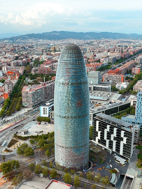 Aerial view of Torre Glòries in Barcelona surrounded by cityscape.