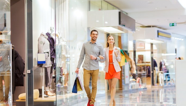 Couple with shopping bags in Yas Mall interior featuring modern architecture and vibrant shopping scene.