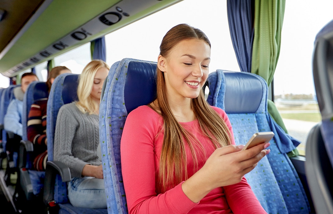 Passengers on a shuttle bus from Amsterdam using mobile devices.