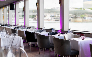 Dining tables set for Le Diamant Bleu Seine River Dinner Cruise in Paris.