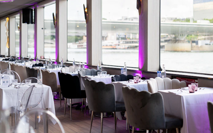 Dining tables set for Le Diamant Bleu Seine River Dinner Cruise in Paris.