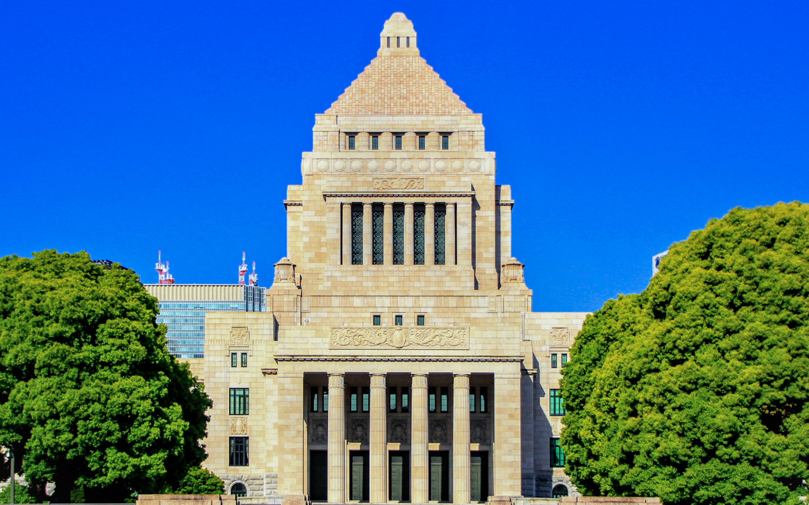 National Diet Building in Tokyo with clear blue sky and surrounding trees.