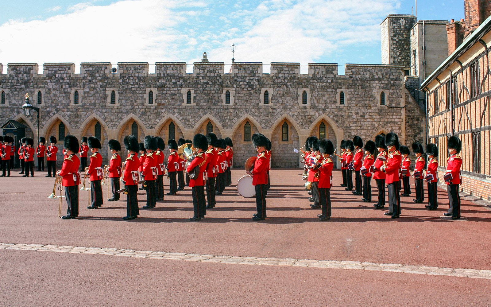 Guards in red uniforms and bearskin hats in formation at Windsor Castle.
