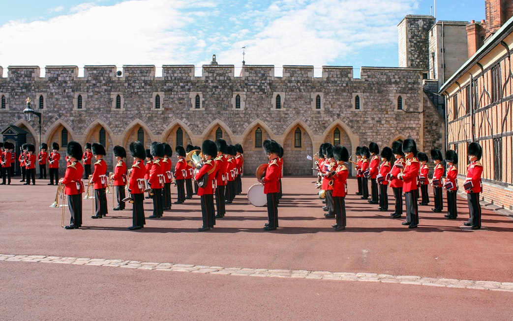 Guards in red uniforms and bearskin hats in formation at Windsor Castle.