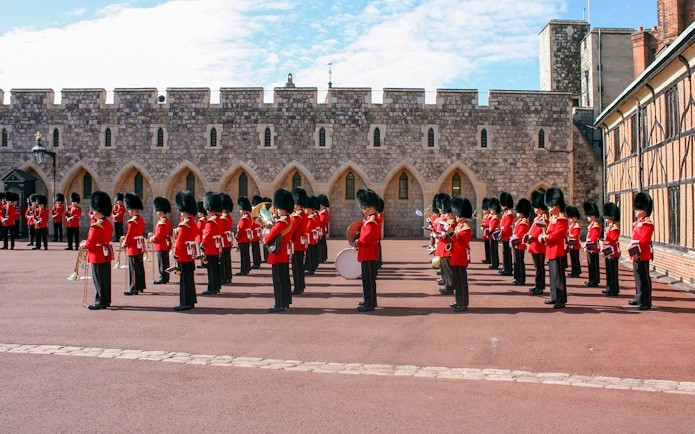 Guards in red uniforms and bearskin hats in formation at Windsor Castle.