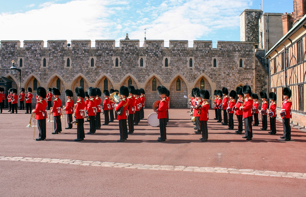Guards in red uniforms and bearskin hats in formation at Windsor Castle.