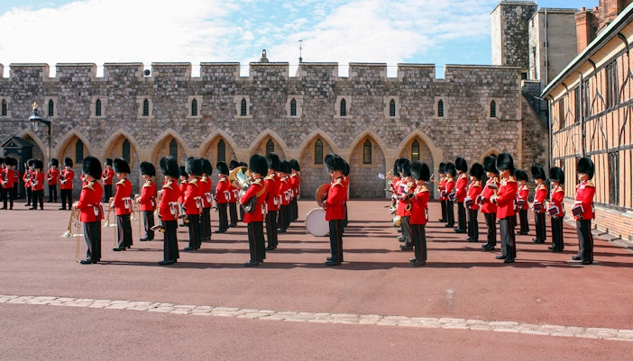 Guards in red uniforms and bearskin hats in formation at Windsor Castle.