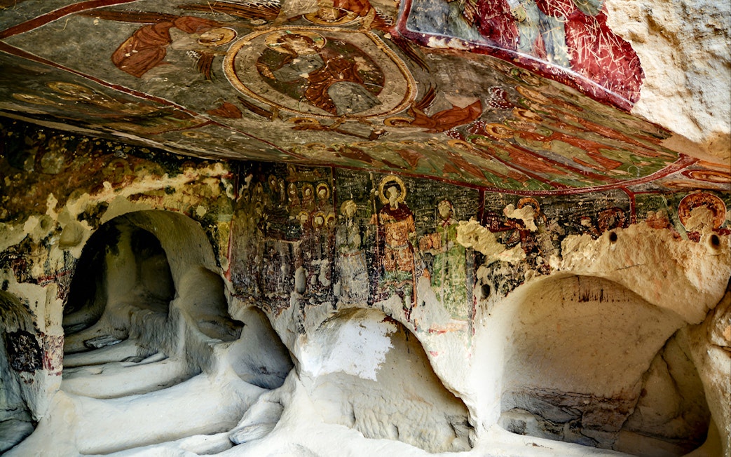 Underground cave church with fresco paintings on walls and ceiling.