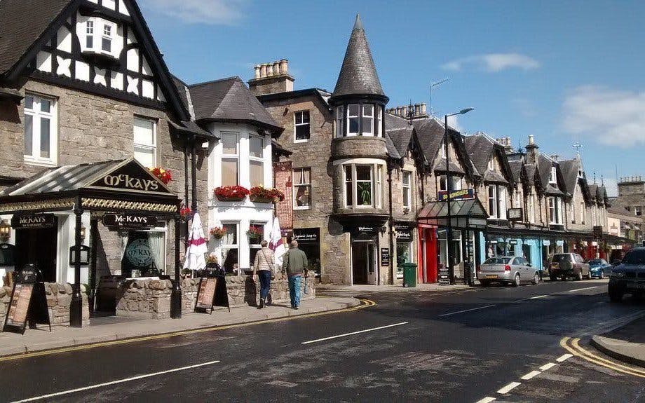 Street view of traditional stone buildings and shops in Pitlochry, Scotland.
