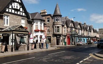 Street view of traditional stone buildings and shops in Pitlochry, Scotland.