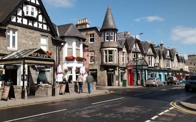 Street view of traditional stone buildings and shops in Pitlochry, Scotland.